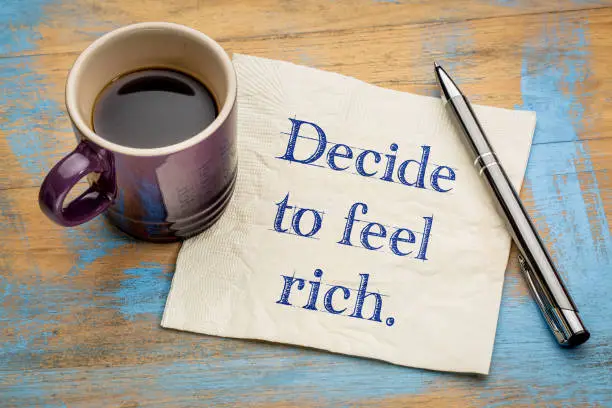 decide to feel rich advice - handwriting on a napkin with a cup of coffee