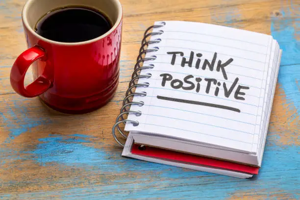 think positive - inspirational handwriting in a notebook with a cup of coffee