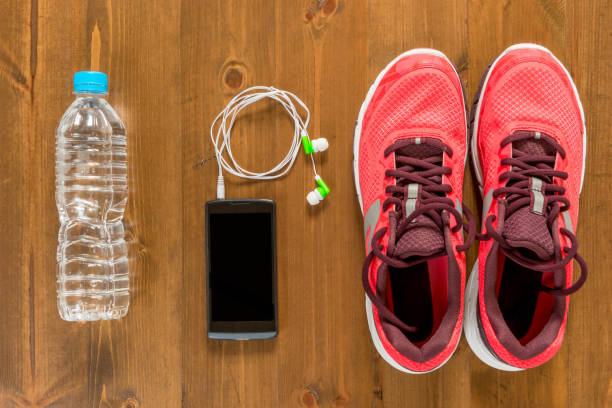 bottle of water, telephone and running shoes for sports on a dark wooden floor view from above close up bottle of water, telephone and running shoes for sports on a dark wooden floor view from above close up running shoes on floor stock pictures, royalty-free photos & images