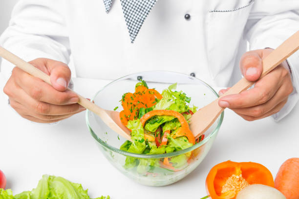 glass bowl with a useful vegetable salad, and cook with a hands spoons