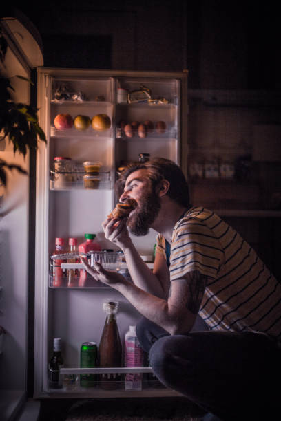 istock Young handsome man eating late night in front of the refrigerator 683125558