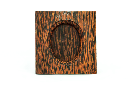 An upright-shaped picture frame is made of wood. The frame is hardwood, brown colored with black stripes. Display of this frame is in oval shaped, with a picture slot on top.