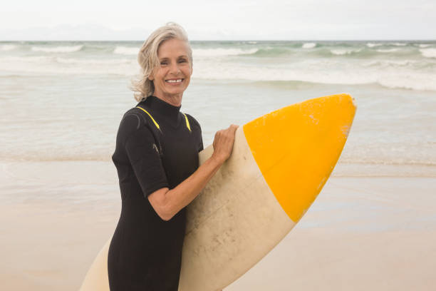istock Portrait of smiling woman carrying surboard while standing on shore 683142226