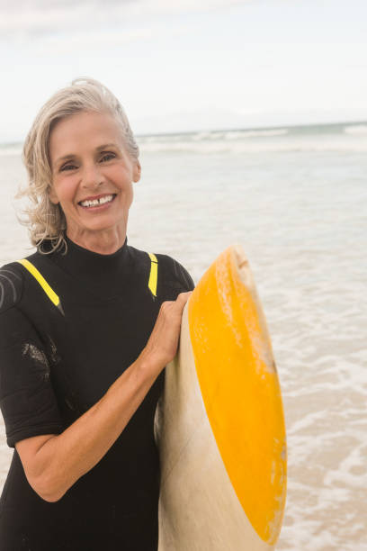 istock Portrait of smiling woman carrying surfboard while standing on shore 683142270