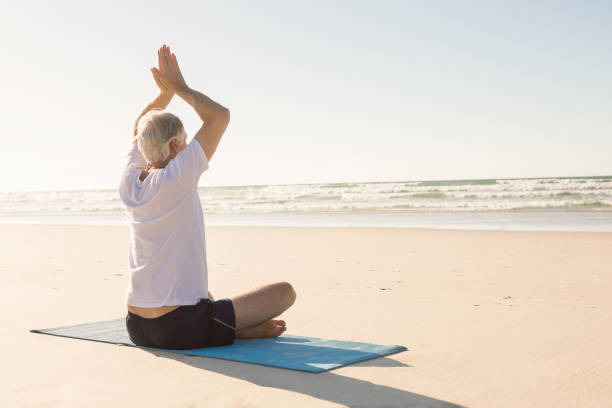 istock Senior man with arms raised meditating at beach 683172148