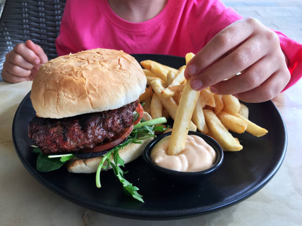 istock Young girl eats a big hamburger with chips 683181886