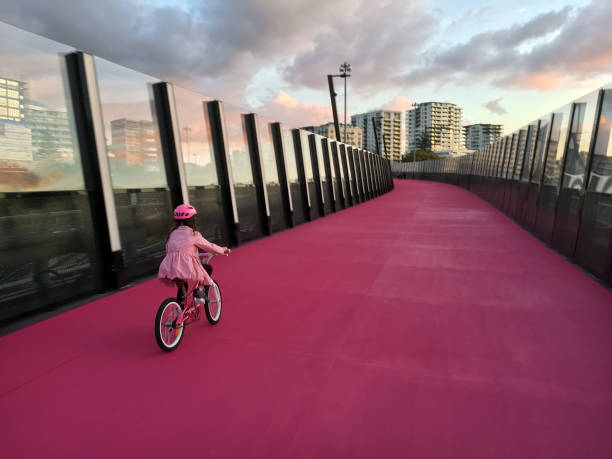 молодая девушка ездить на велосипеде на ярко-розовый велодорожка в окленде новая зеландия - pink city стоковые фото и изображения