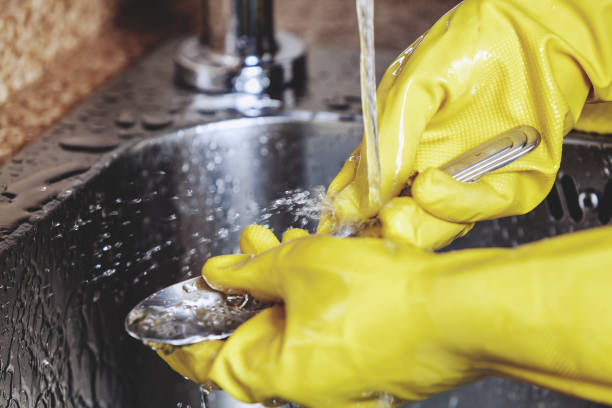 istock Hands in yellow rubber gloves, wash spoon in sink 683188064