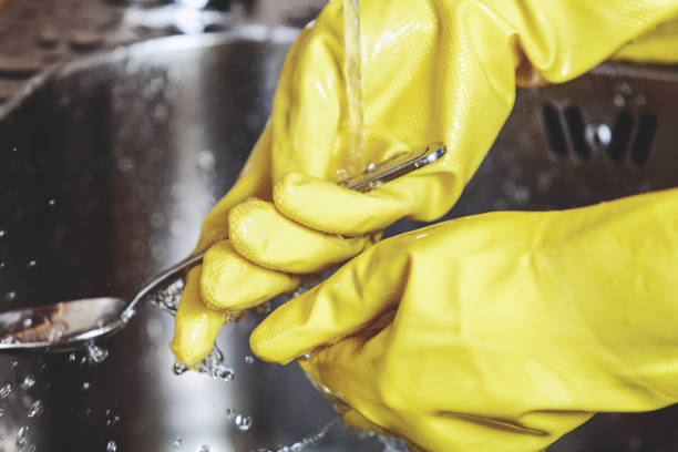 istock Hands in yellow rubber gloves, wash spoon in sink 683188148
