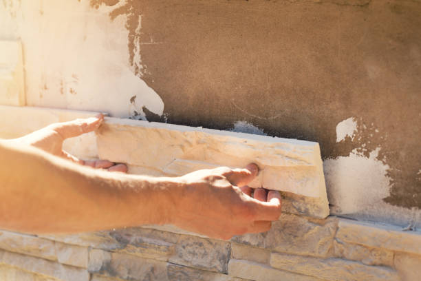 istock worker installing decorative stone tiles on house facade 683191188
