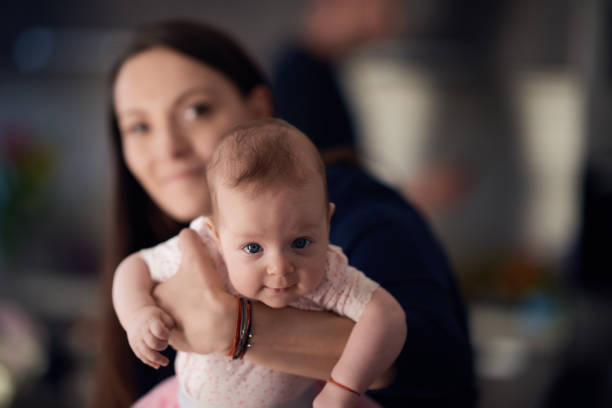 portrait of cute baby girl in her mother arms looking at camera. family time and love.