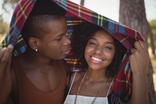 Close up of smiling couple in blanket at forest