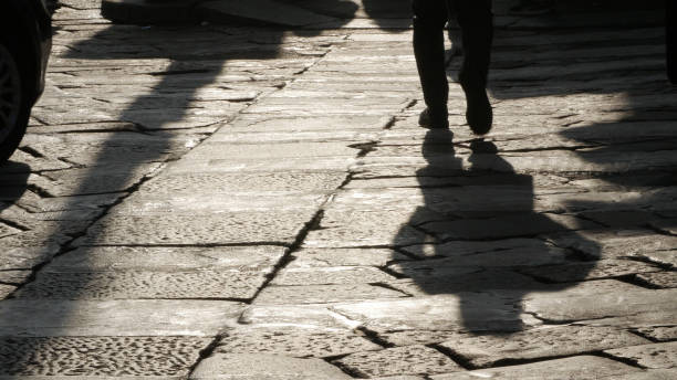 istock Silhouettes of people on the cobblestone pavement 683249836