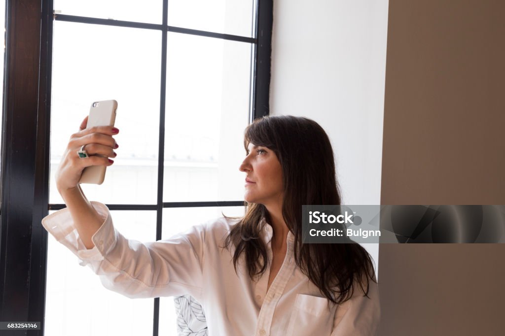 Beautiful business woman taking a selfie by the window Adult Stock Photo