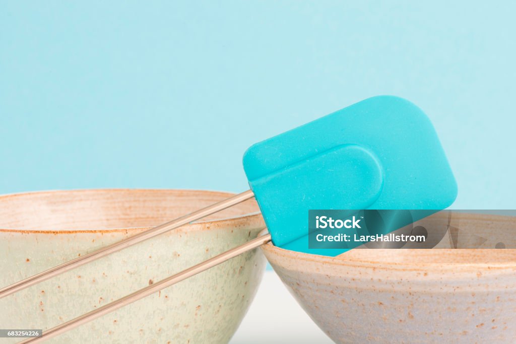 Kitchen bowl and dough scraper Kitchen bowl and dough scraper on table. Concept of baking, cooking and food preparation. Clean blue background with copyspace. Rubber Spatula Stock Photo