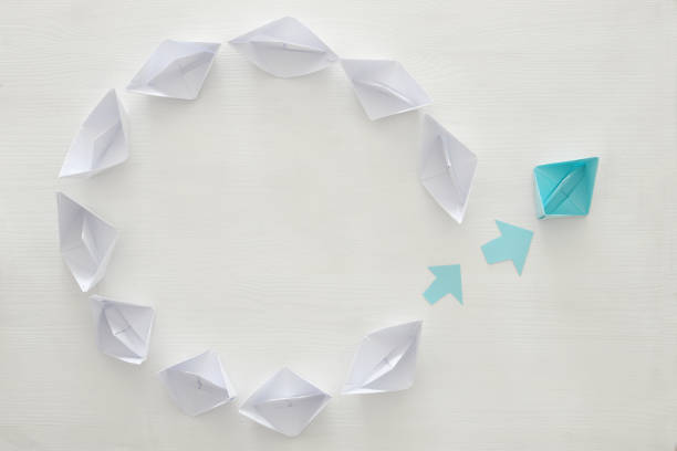 istock paper boats and one individual boat choosing different path 683257666