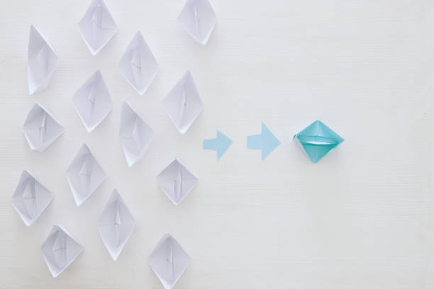istock paper boats and one individual boat choosing different path 683257668
