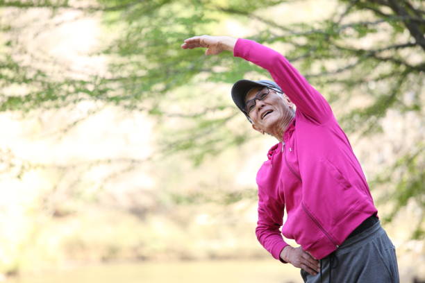 istock senior Japanese man in pink wear doing standing side bend exercise 683268132