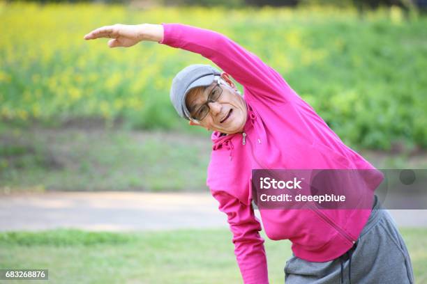 Senior Japanese Man In Pink Wear Doing Standing Side Bend Exercise Stock Photo - Download Image Now