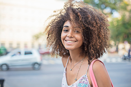 Portrait of happy woman in city. Young smiling female standing outdoors. She is wearing casuals.