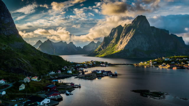 Aerial shot of Reine village and fjord in front of the mountains of Moskenesoya at the Lofoten Islands in Norway. The Lofoten Islands are known for a distinctive scenery with dramatic mountains, open sea and sheltered bays, beaches and untouched lands.