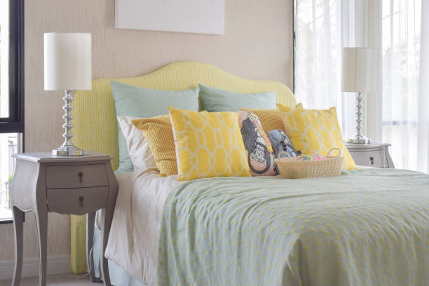 istock Classic style bedside table with reading lamp next to cozy style bedding with many style of green and yellow pillows 683299582