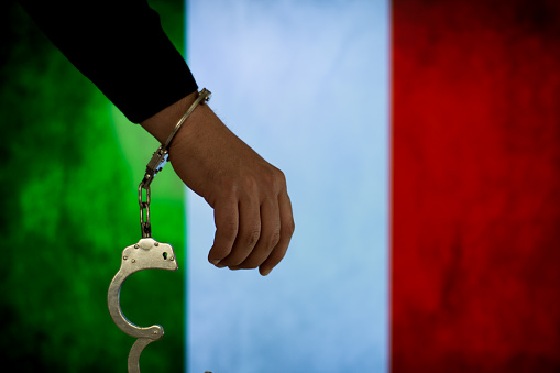 Handcuffs with hand in front of flag