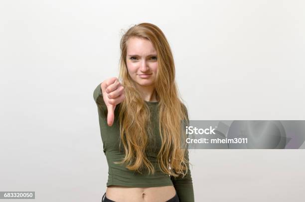 Rebellious Negative Woman Giving A Thumbs Down Stock Photo - Download Image Now - Adult, Adults Only, Anger