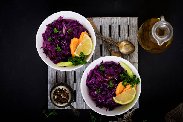 istock Stewed red cabbage with carrots and celery in a white bowl on a black background. Flat lay. Top view 683333556