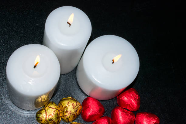 istock On a dark background there are two burning white candles and chocolates 683339330