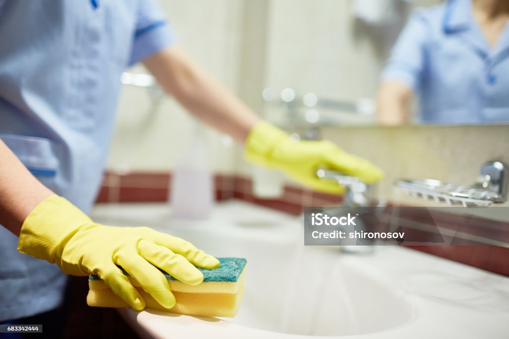 Cleaning sink with sponge Janitor cleaning sink in hotel room Cleaning Stock Photo