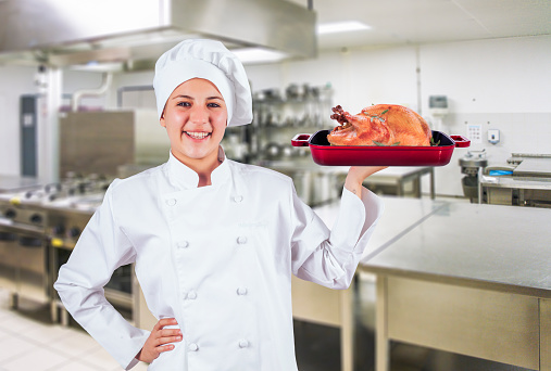 Female chef presenting roasted turkey in an commercial kitchen