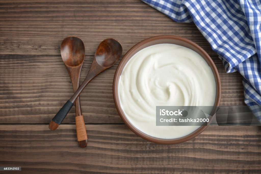 Yogurt in bowl Yogurt in bowl with spoon on wooden background, top view Yogurt Stock Photo