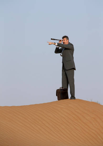 istock man in a suit in a desert with a spyglass 683346638
