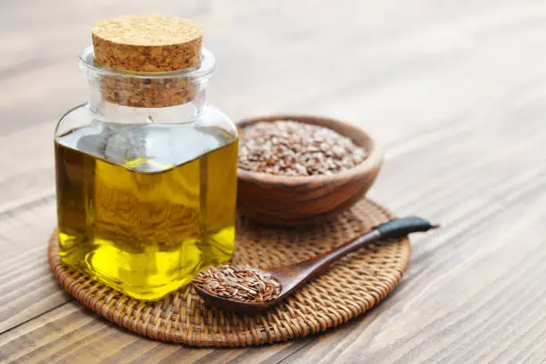 Flax seeds and oil in bottle on wooden background