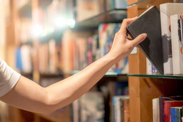 istock Right hand of young man picking a book from bookshelf in library 683349600
