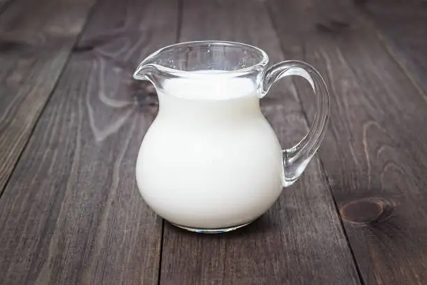Milk in a glass jug on a wooden background. Bio products. Food.