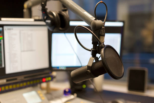 Studio microphone in front of radio station broadcasting equipment Studio microphone in front of a sound mixer and computers in broadcasting radio studio. New radio station studio. volume knob photos stock pictures, royalty-free photos & images