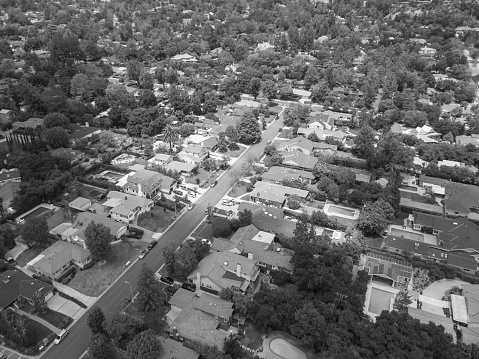 An aerial shot of a sunny and tree filled neighborhood.