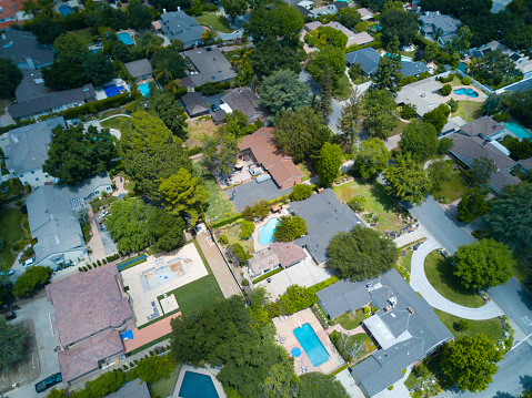 An aerial shot of a sunny and tree filled neighborhood.