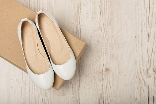 Women shoes (ballet flats) white color on a light wooden background. Selective focus.