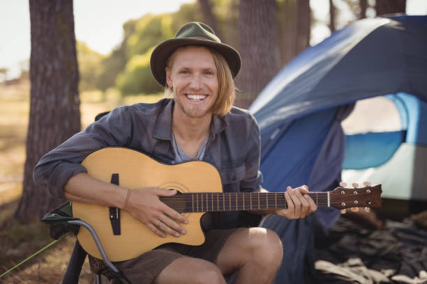 istock Portrait of smiling young man playing guitar while sitting on chair 683401834