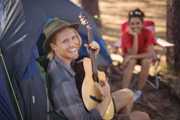 istock Portrait of smiling man playing guitar while his girlfriend sitting in background 683402326