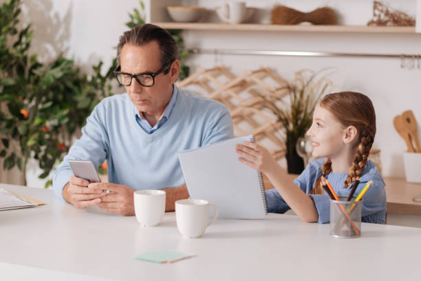 istock Involved grandfather ignoring granddaughter while using phone indoors 683412548