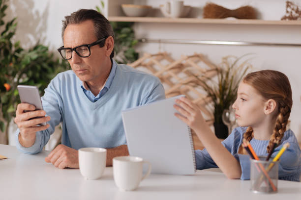 istock Concentrated businessman ignoring granddaughter while using phone indoors 683412584