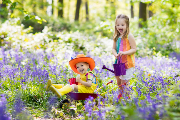 istock Kids with bluebell flowers, garden tools 683417744