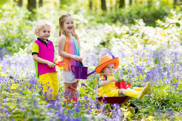 istock Kids with bluebell flowers, garden tools 683421038