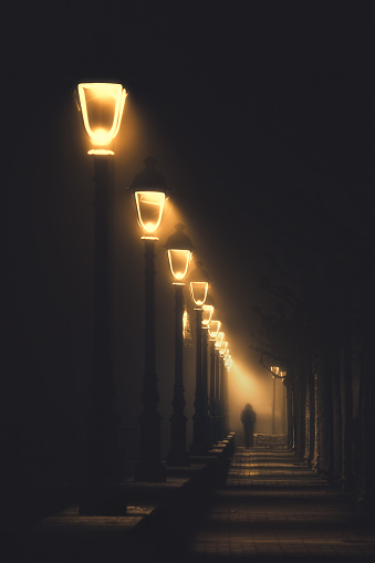 persona caminando en la calle oscura iluminada con farolas photo