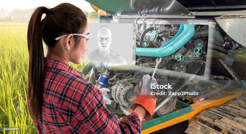 Augmented reality glasses technology , smart agriculture farm , artificial intelligence adviser, industry 4.0 concept.Young female farmer use Ar glasses to fix tractor car machine with digital screen. Augmented Reality Stock Photo