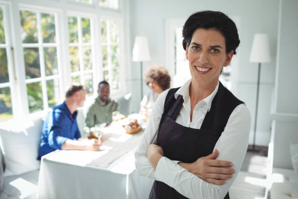 istock Smiling waitress standing with arms crossed 683432136